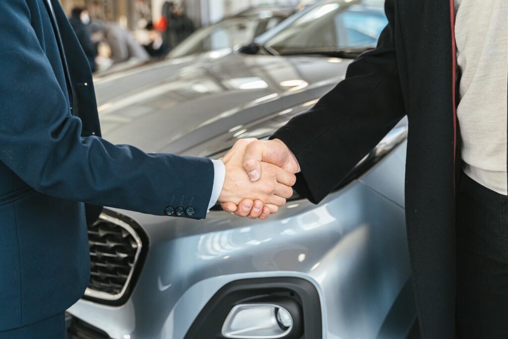 pexels-photo-7144204-7144204 A close-up of two people shaking hands in front of a car in an indoor setting.